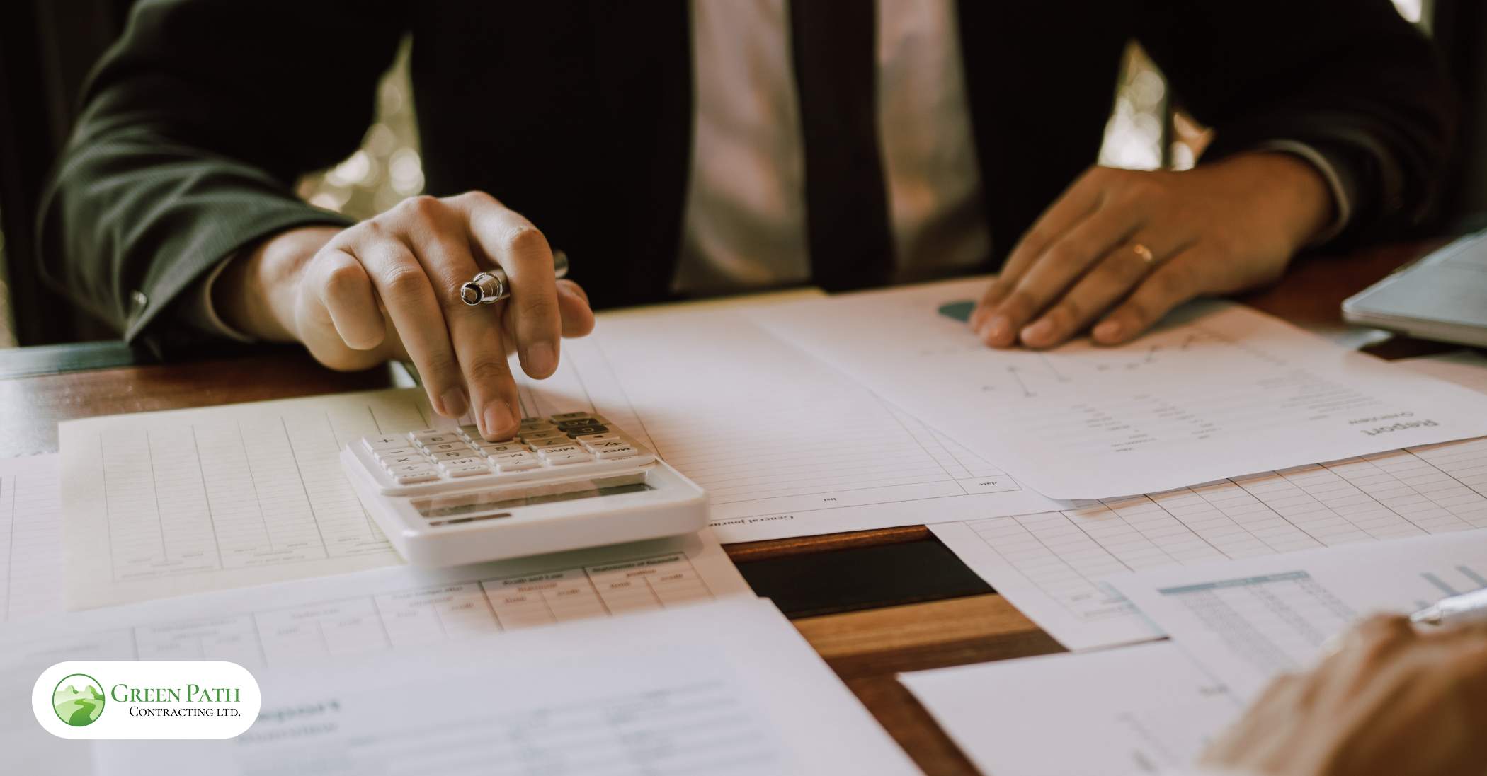 A person engaged in work with a laptop and calculator, evaluating the costs associated with maintaining a laneway house